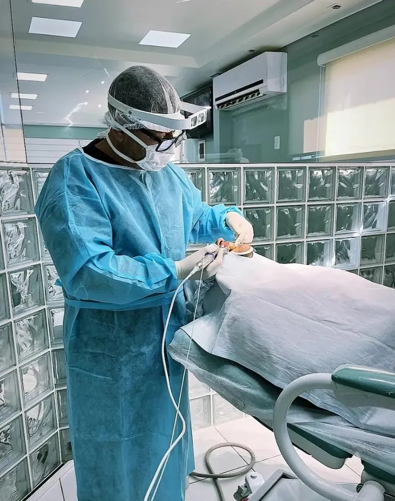 Dr. Radamés com avental cirúrgico na sala de cirurgia da clínica